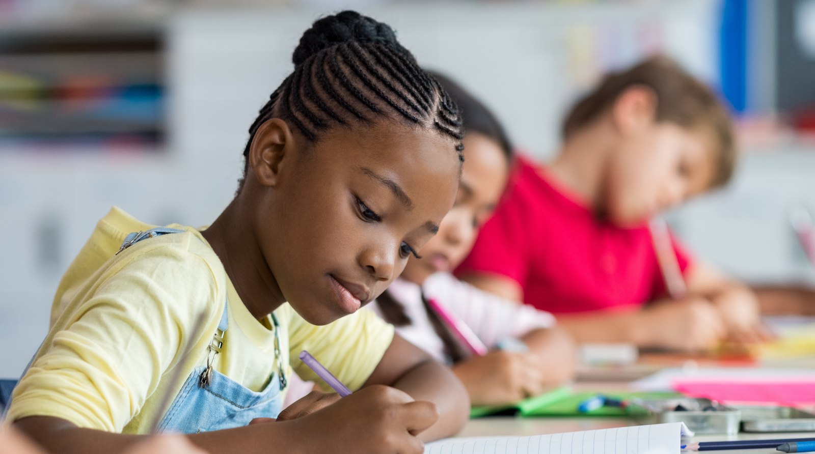 A girl focused on writing in class — why autism and ADHD in girls are so often missed