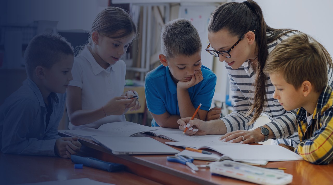 Teacher working with a group of primary pupils around a table &mdash; SEND training package delayed to 2027